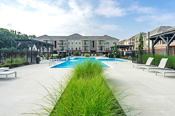 A pool area with a grassy divider in the foreground and a building in the background.